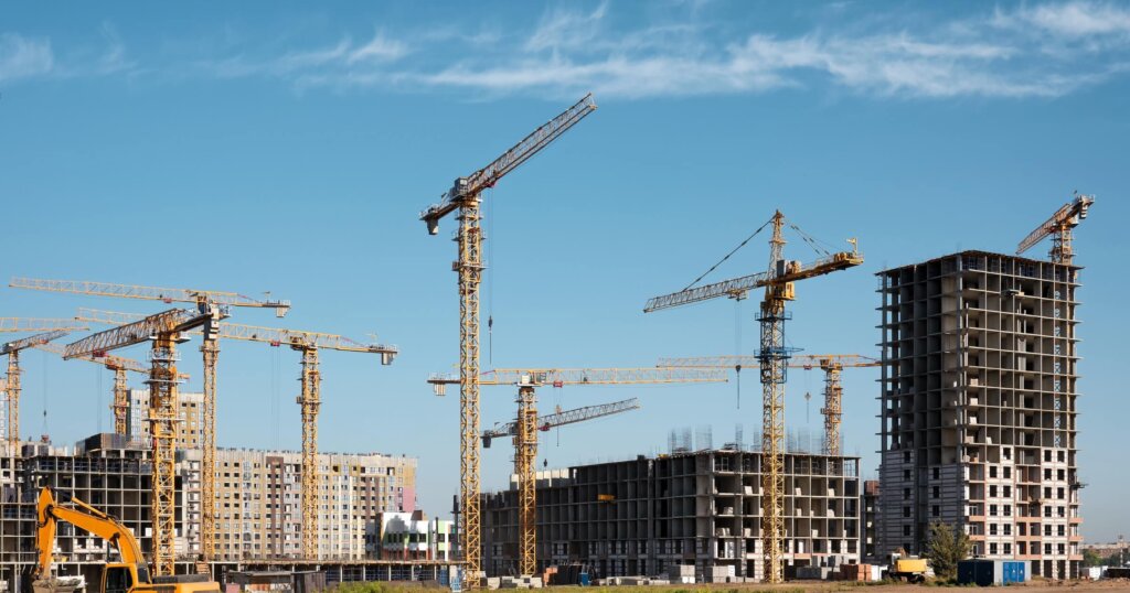 Construction of a new residential complex. Many high-rise cranes and industrial construction equipment against the backdrop of a construction buildings.
