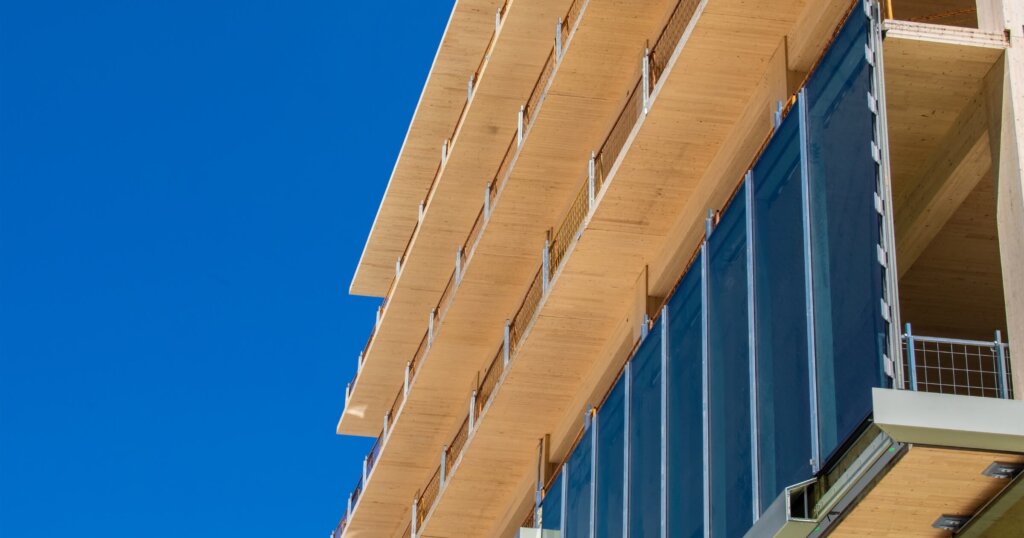 Glass curtain wall being installed on an engineered timber multi story green, sustainable, residential high rise apartment building construction project