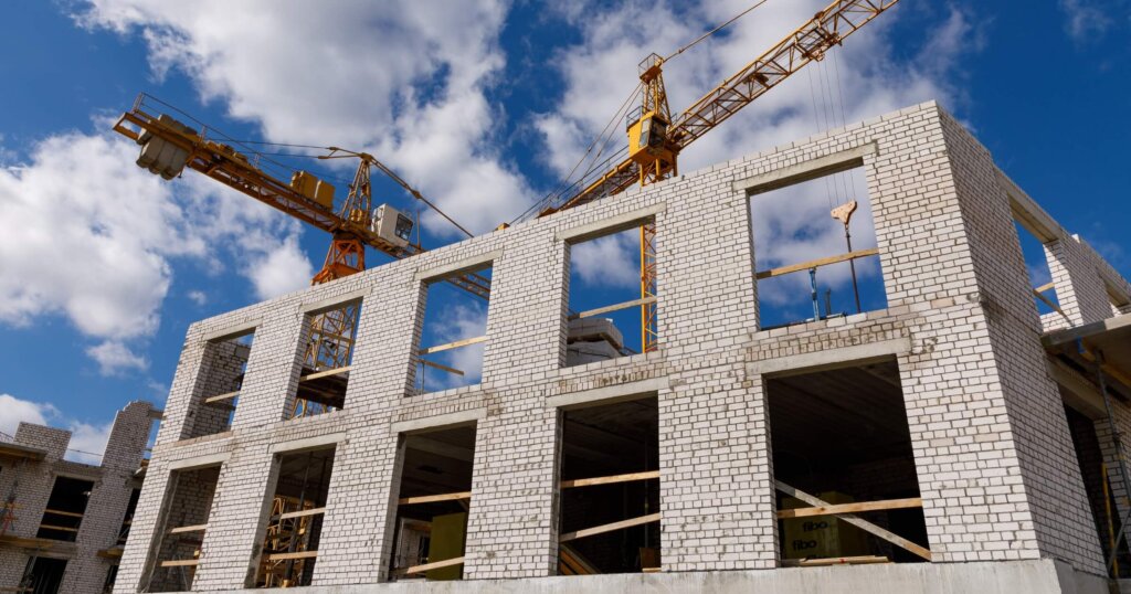 Unfinished construction of a multi-storey residential building and a tall crane.