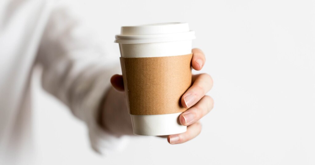 A cup of coffee being held by a hand