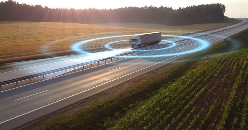 Aerial view of autonomous truck driving on autopilot on a highway with traffic sensors scanning surroundings. Cargo delivery, transportation of the future. Artificial intelligence. Self driving.