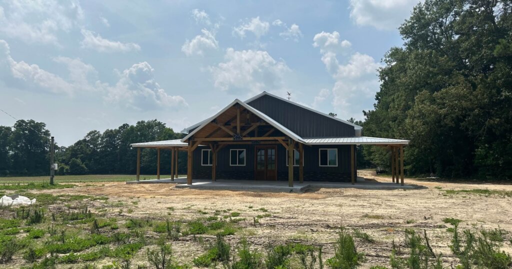 Post frame construction pole barn garage with living space, concrete floor, metal walls and roofing, two lean-to’s and front porch.