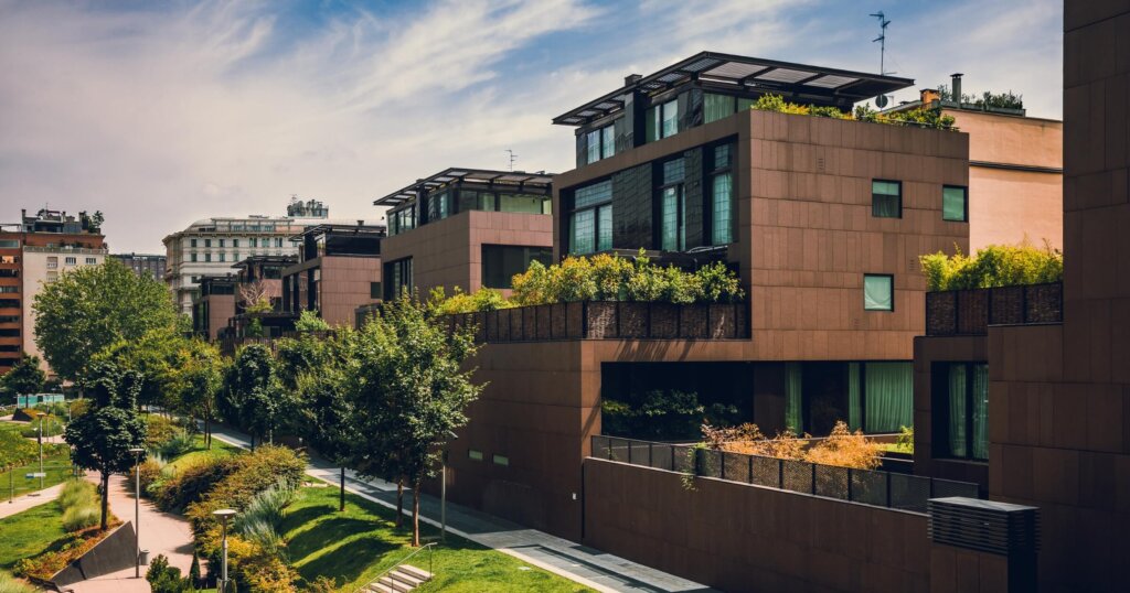 Modern residential buildings in the public green area. Apartment houses in Europe. Beautiful view of real estate homes in Milan, Italy. Business district in summer. Walking area with trees and grass.