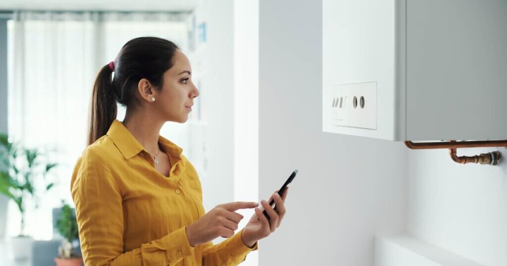 Woman managing and programming her smart boiler using her smartphone, smart home concept