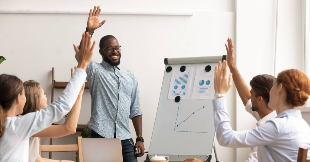 Business team voting concept, smiling african coach leader and diverse employees group raise hands up engaged in volunteering making unanimous decision participate in corporate presentation training.