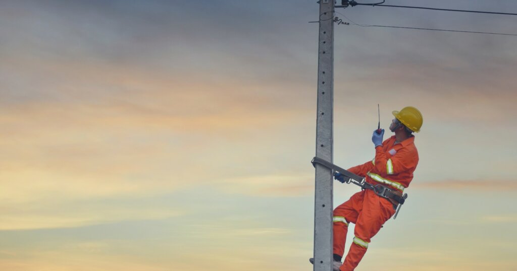Installation of switching and connecting overhead electrical lines on a pole. An electrician is working on a pole. Linemen.