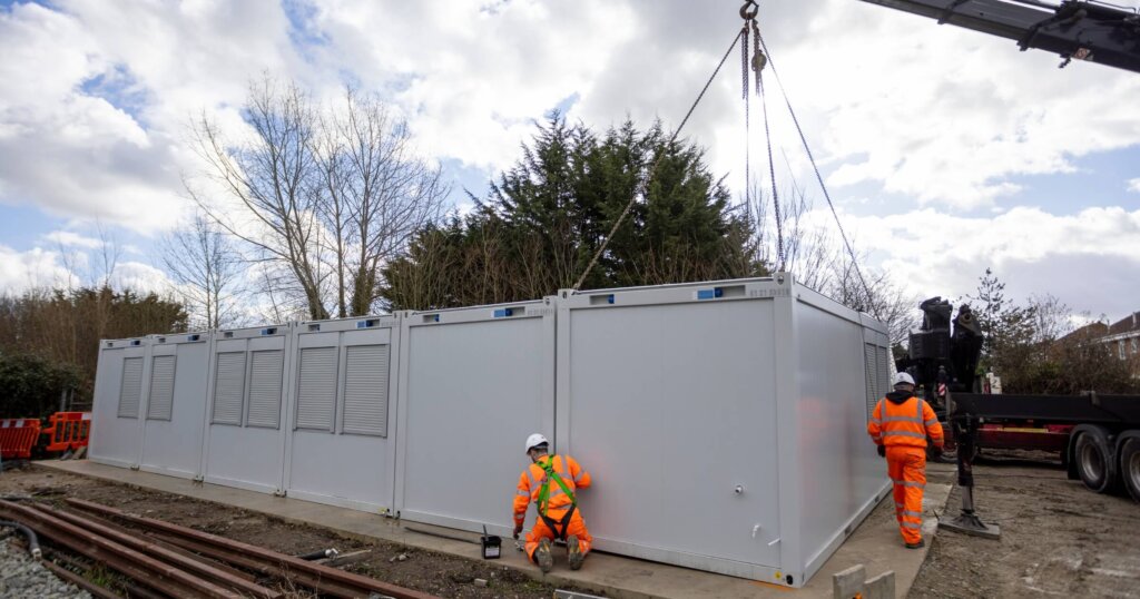 Edenbridge, England - 08.15.2021: Construction workers in High Visibility clothes Assembling a Shipping Container style Modular Building.