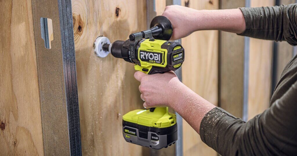 ryobi hammer drill in use drilling a hole into a wood fence