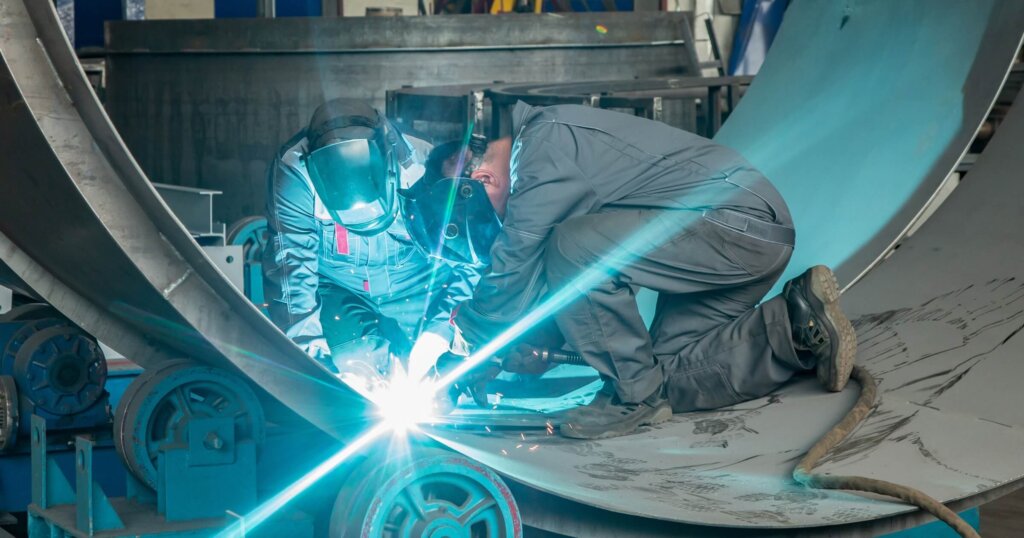Two workers while doing a welding with arc welder.