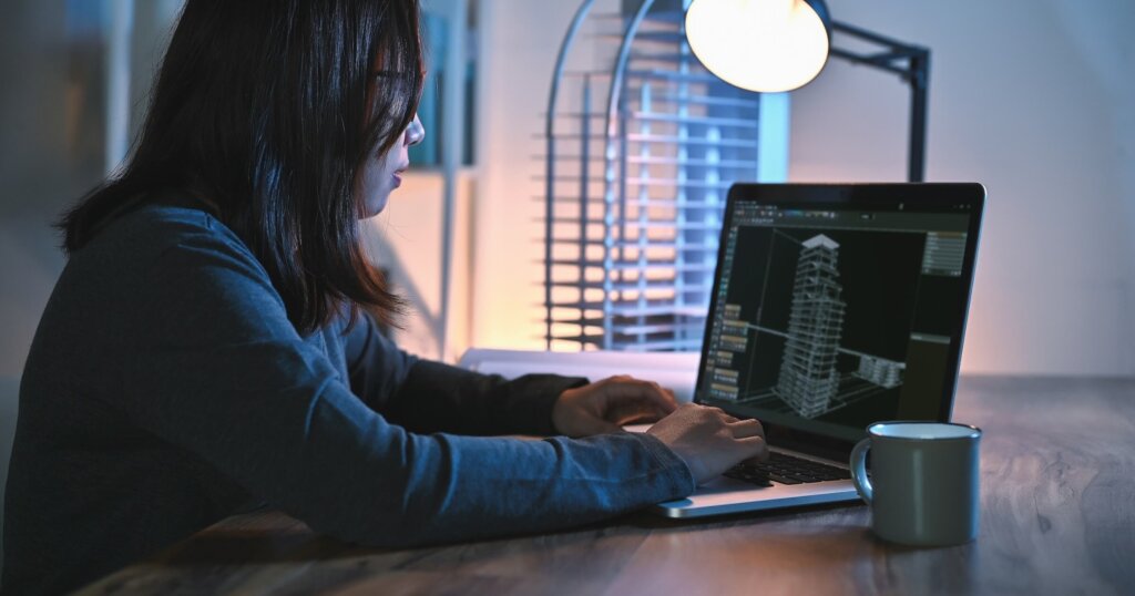 Asian women engineer use laptop study detail and construction design alone in BIM in an office room at night with building model on desks office.