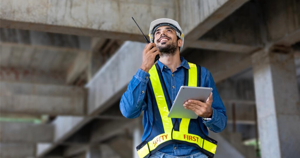Caucasian building inspector with radio walkie talkie in full safety gear is inspecting inside the building structure for investigation over specification and quality control usage.