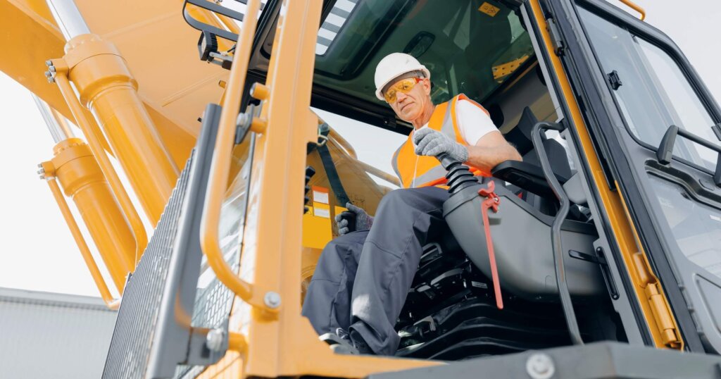 Heavy machine operator operating an excavator at construction site.