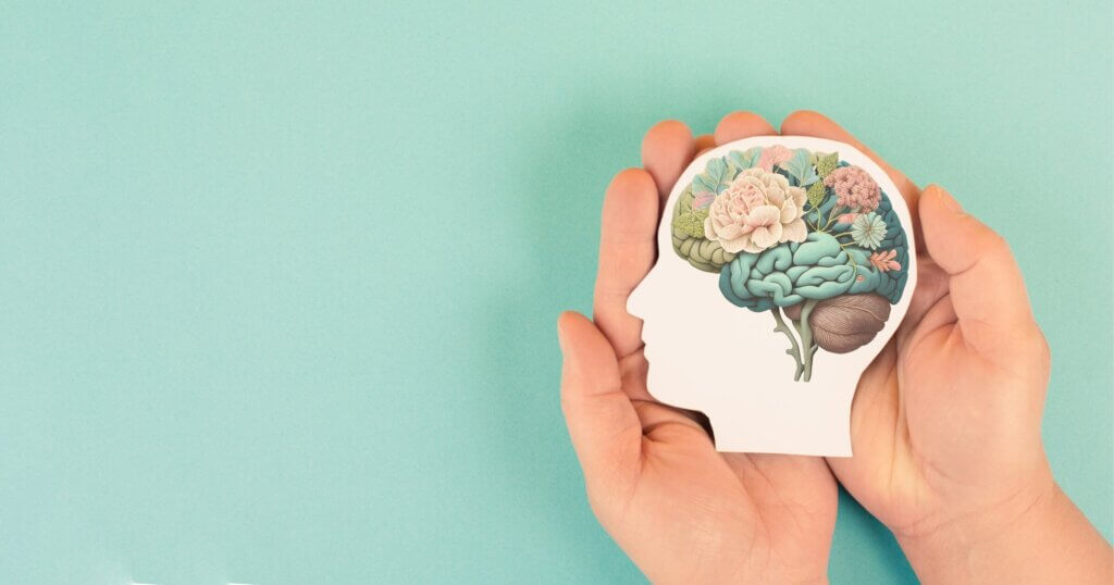 Hands holding paper head, human brain with flowers, self care and mental health concept, positive thinking.