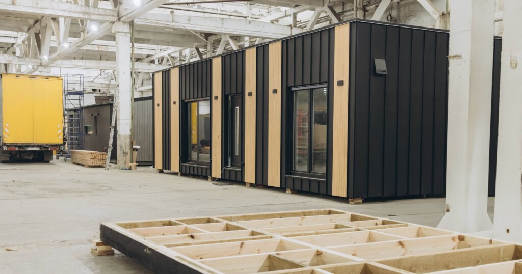 Modular house being built inside a factory, showing the wooden frame and the almost complete module.