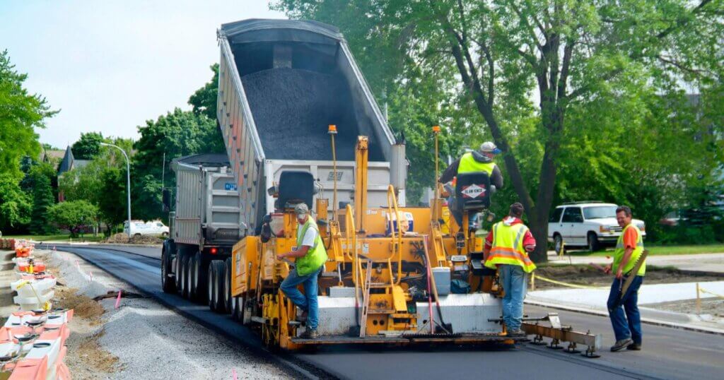 Construction crew Wearing colorful yellow safety vest  creates new asphalt streetin port Huron Michigan.