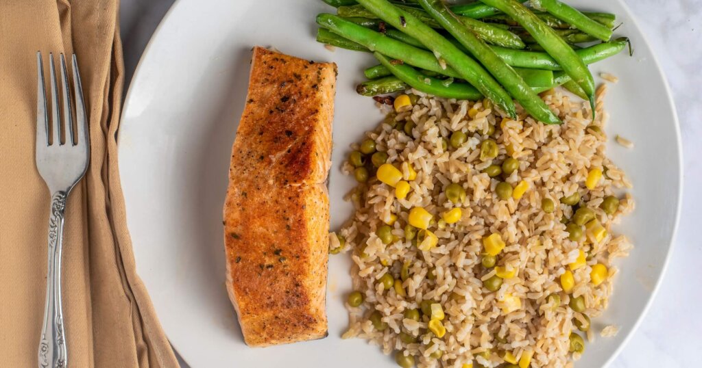 Salmon with brown rice and steamed greens on a table.