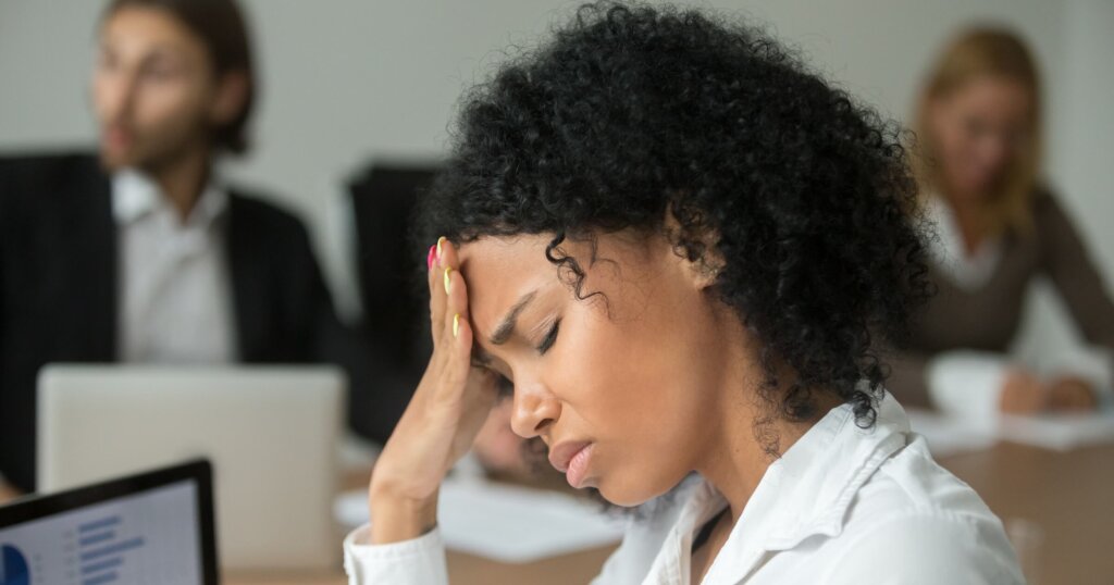 African american businesswoman feeling unwell suffering from headache migraine touching forehead at team meeting, upset black woman employee frustrated by business problem or work stress, head shot