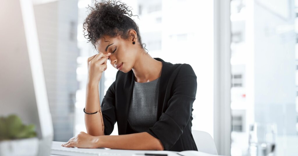 Business, black woman and tired with headache in office from migraine, overworked and stress for work deadline. Professional, employee and mental health with anxiety, burnout and fatigue from project