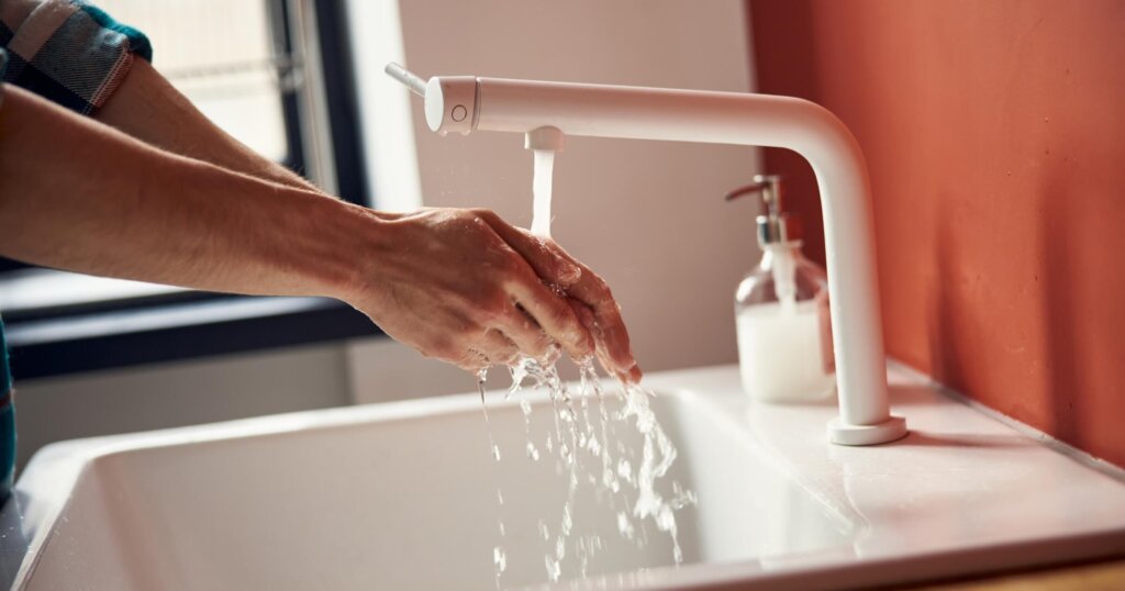 Close up of guy cleaning hands in sink under running slow running water stock photo