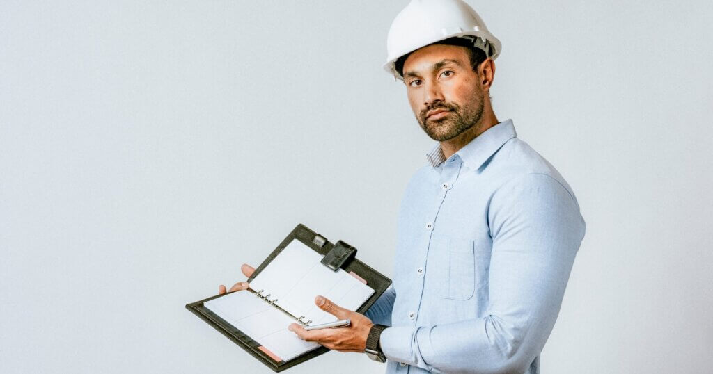 Engineer with a safety helmet showing his planner