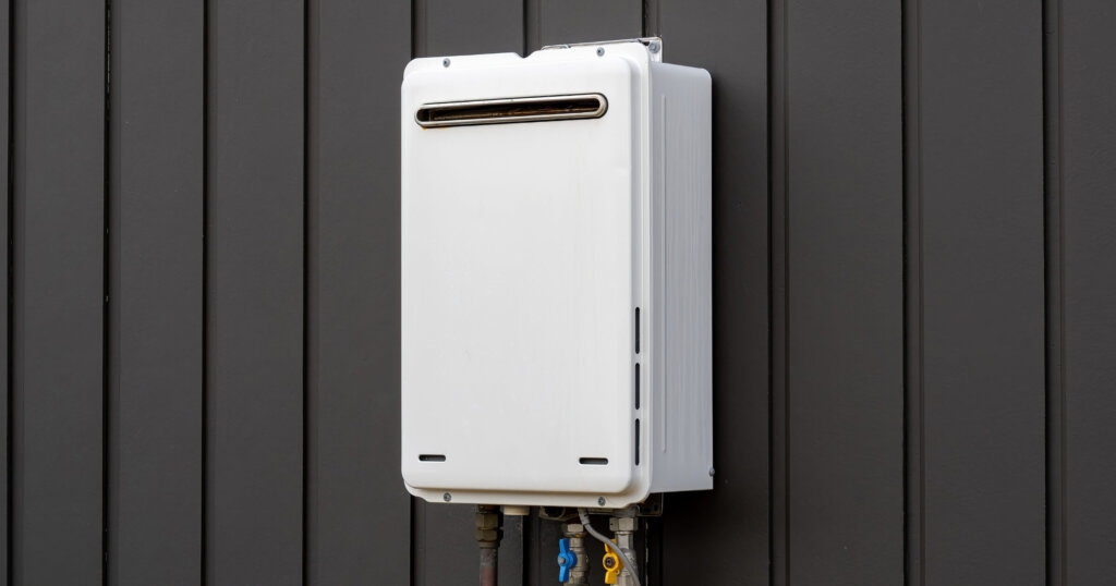 Modern external continuous flow gas water heater mounted on house wall.