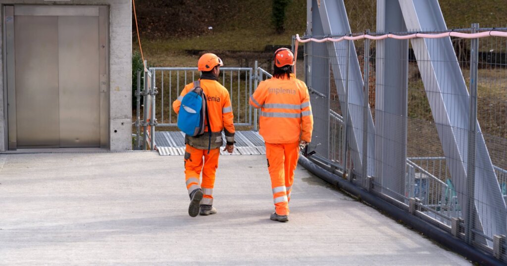 Two construction workers with high visibility clothing leaving