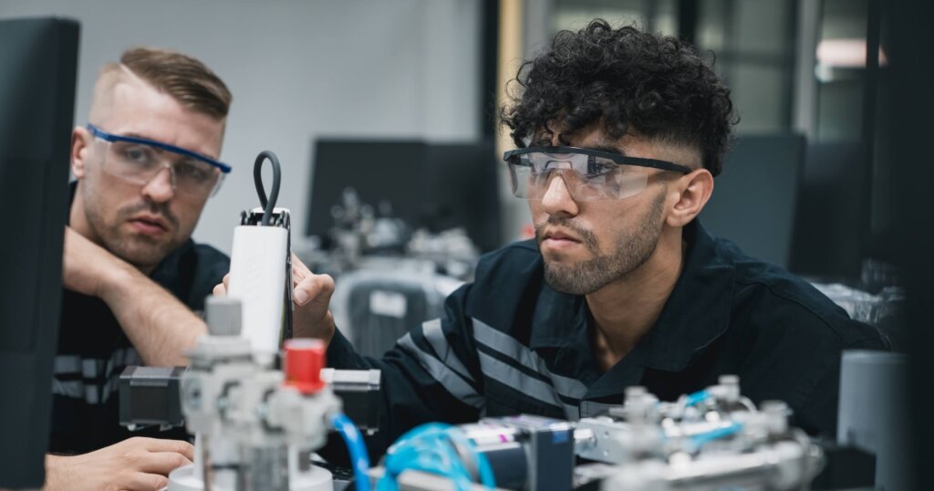 Engineering student assembling a robotic arm using a computer