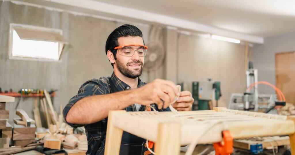 Carpenter working with electric planer on wooden plank in workshop. Craftsman makes own successful small business, man using tool in carpenter's shop to making a furniture from wood