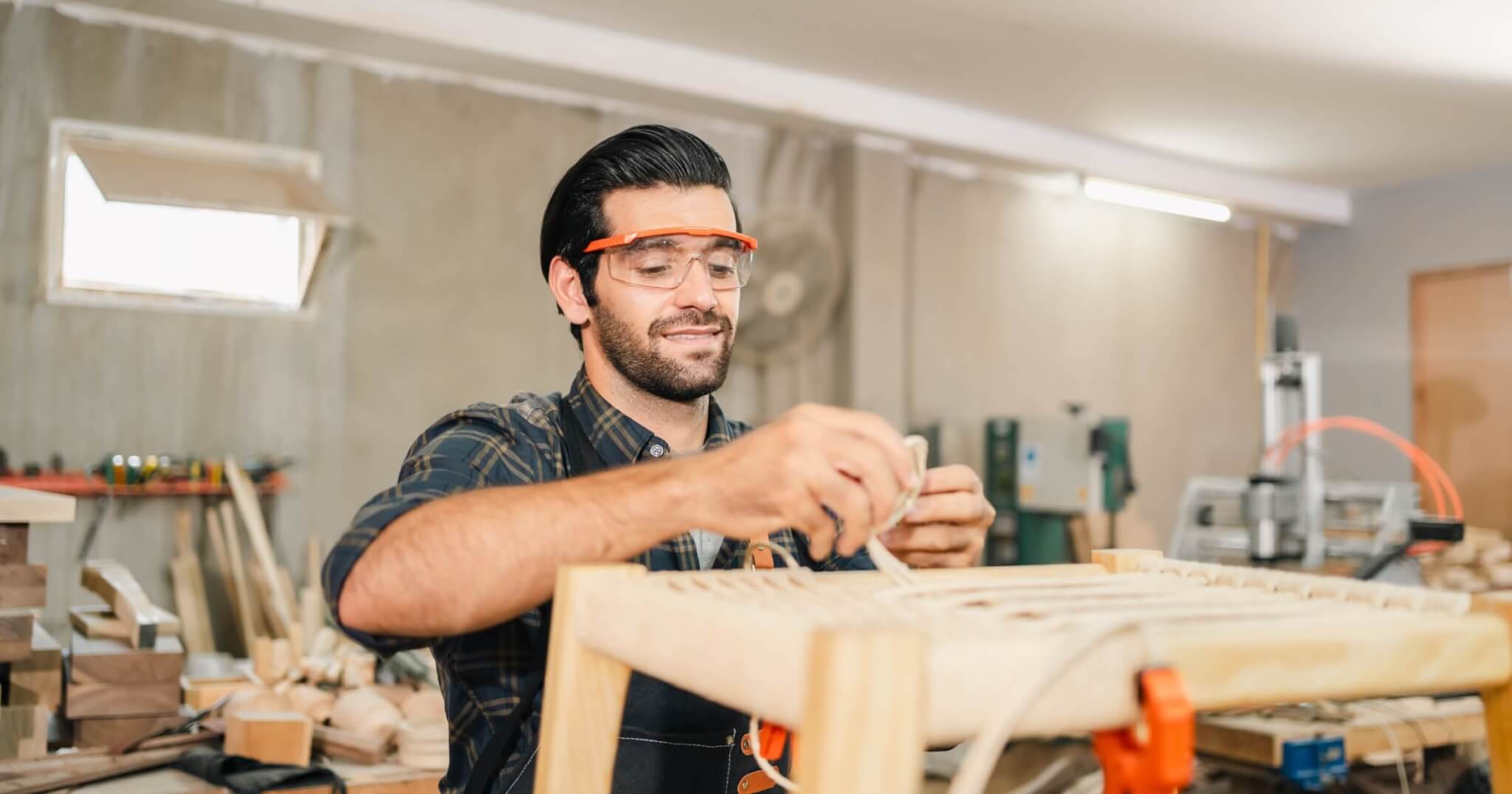 Carpenter working with electric planer on wooden plank in workshop. Craftsman makes own successful small business, man using tool in carpenter's shop to making a furniture from wood
