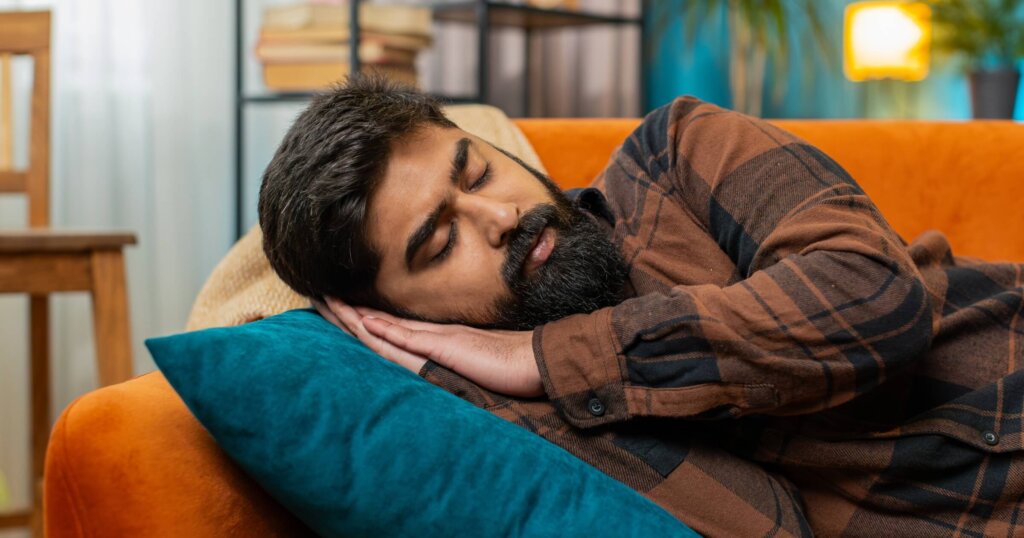 Tired man lying down in bed taking a nap.