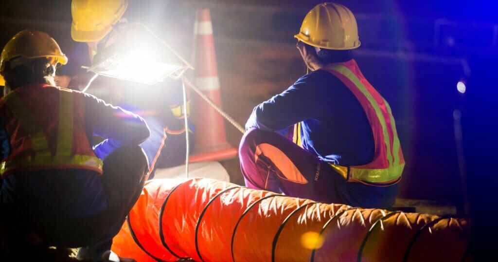 construction worker is working at night in construction site with spotlight and ventilation pipe for working in the underground tunnel, The concept of hard work and over time.