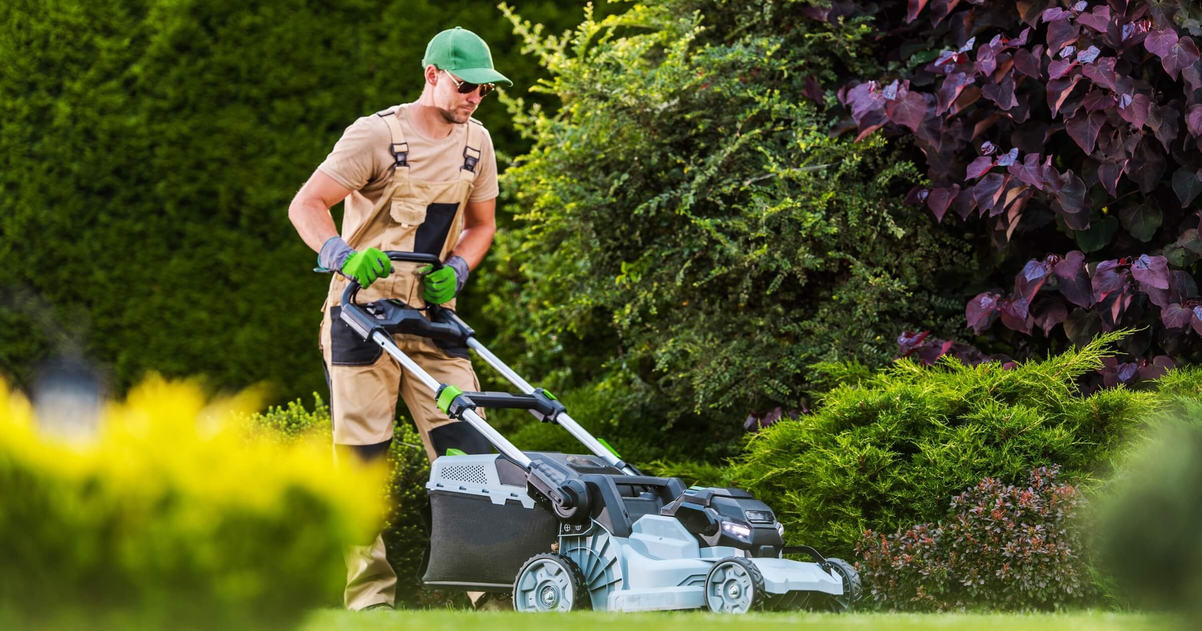 Professional Gardener Mowing the Lawn with Cordless Battery Powered Electric Mower.