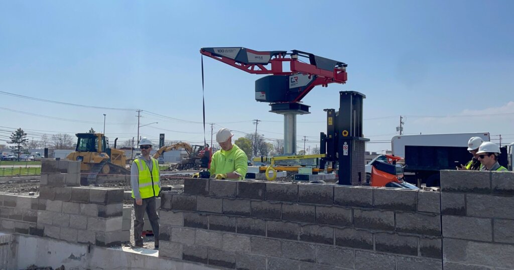Construction Robotics SAM helping workers lay down bricks