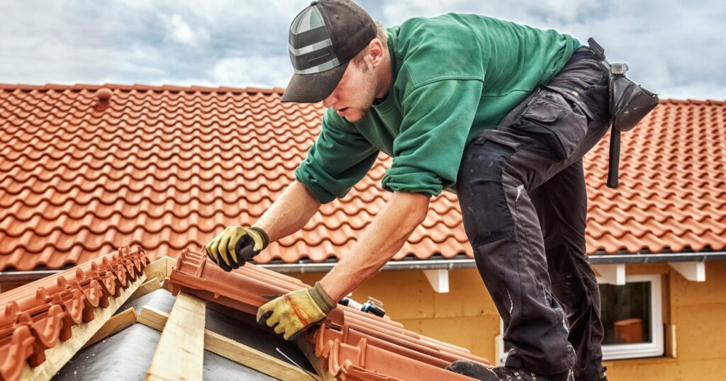 Roofer at work, installing clay roof tiles