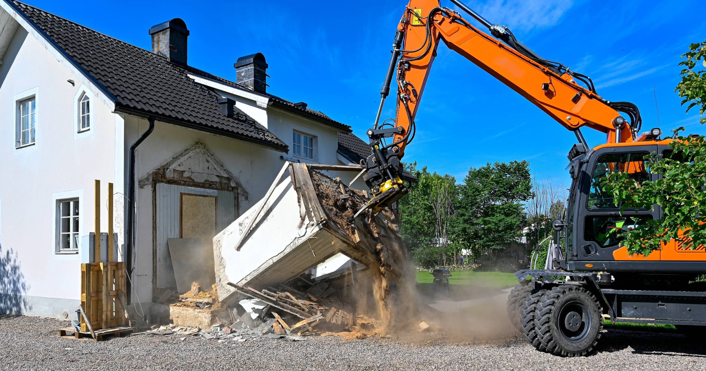 Big orange excavator demolishing part of house