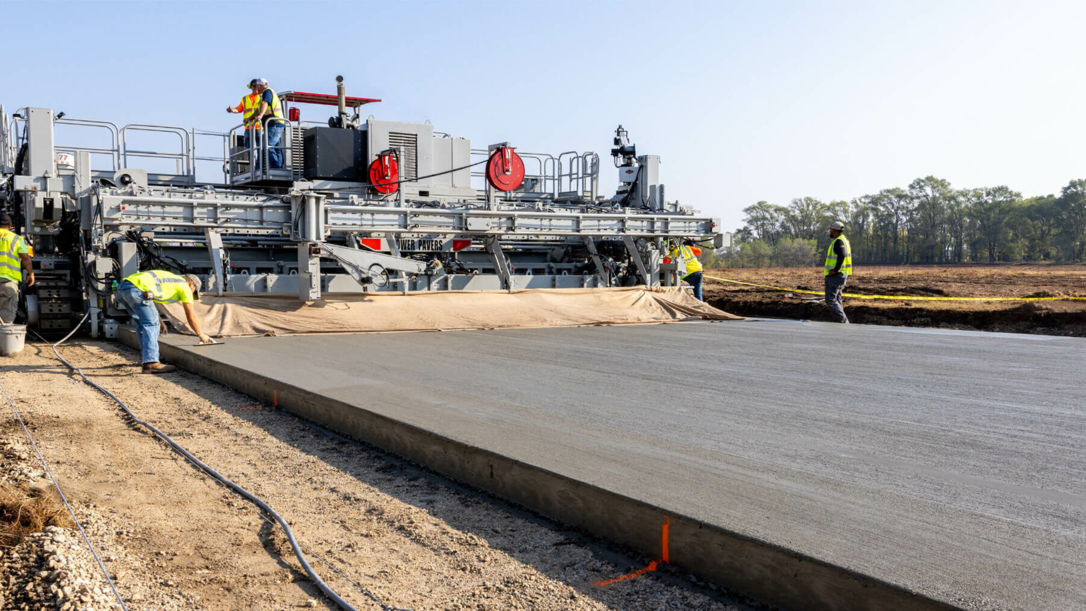 Concrete paving machine workers on road