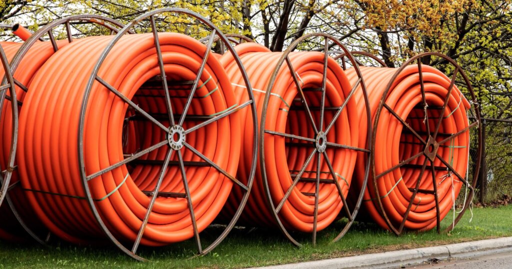 Spools of orange fiber optic conduit on a mobile reel for fiber optic cable installation