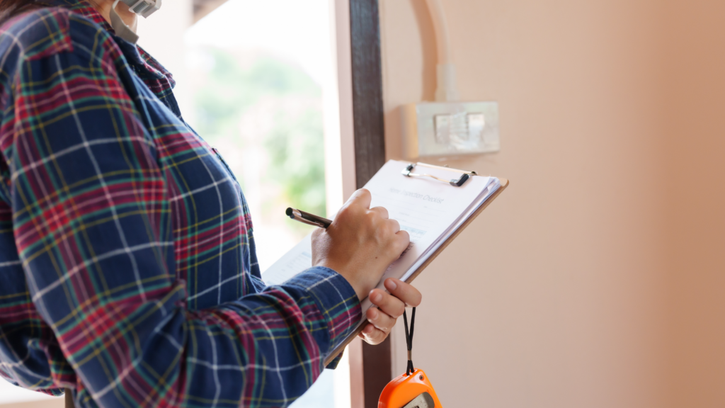 Woman holding a clipboard and rape measure completing a home inspection