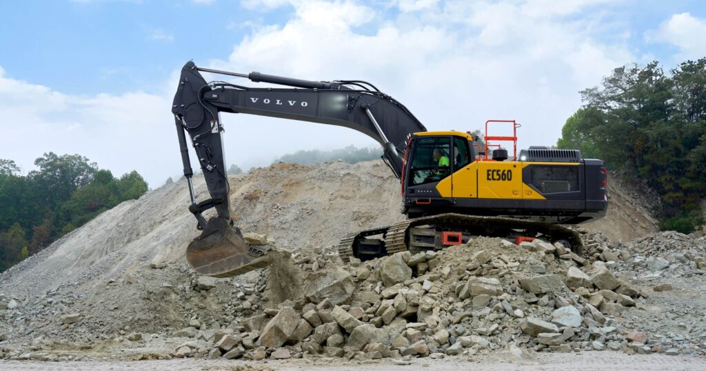 Volvo EC560 excavator operating on a rocky jobsite, moving and sorting earth and aggregate.