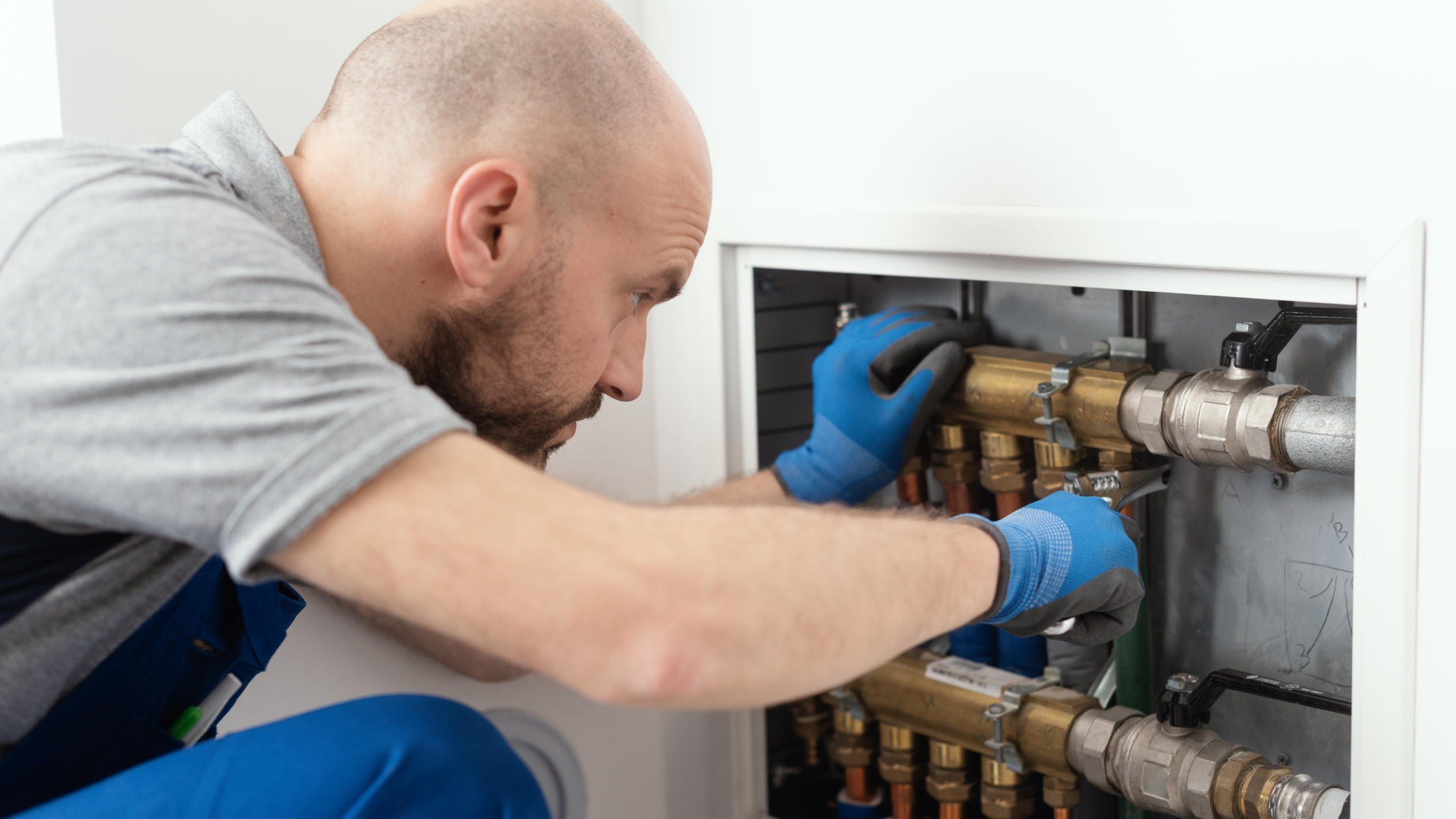 Plumber working on lines in small wall cavity