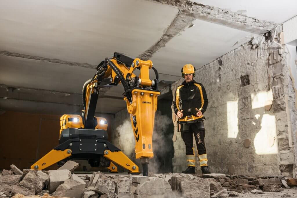 Brokk SmartPower+ remote-controlled demolition robot breaking concrete while operator controls machine from safe distance on active demolition site