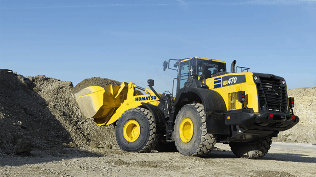 Komatsu WA470-8 wheel loader scooping aggregate material from large stockpile on open construction site